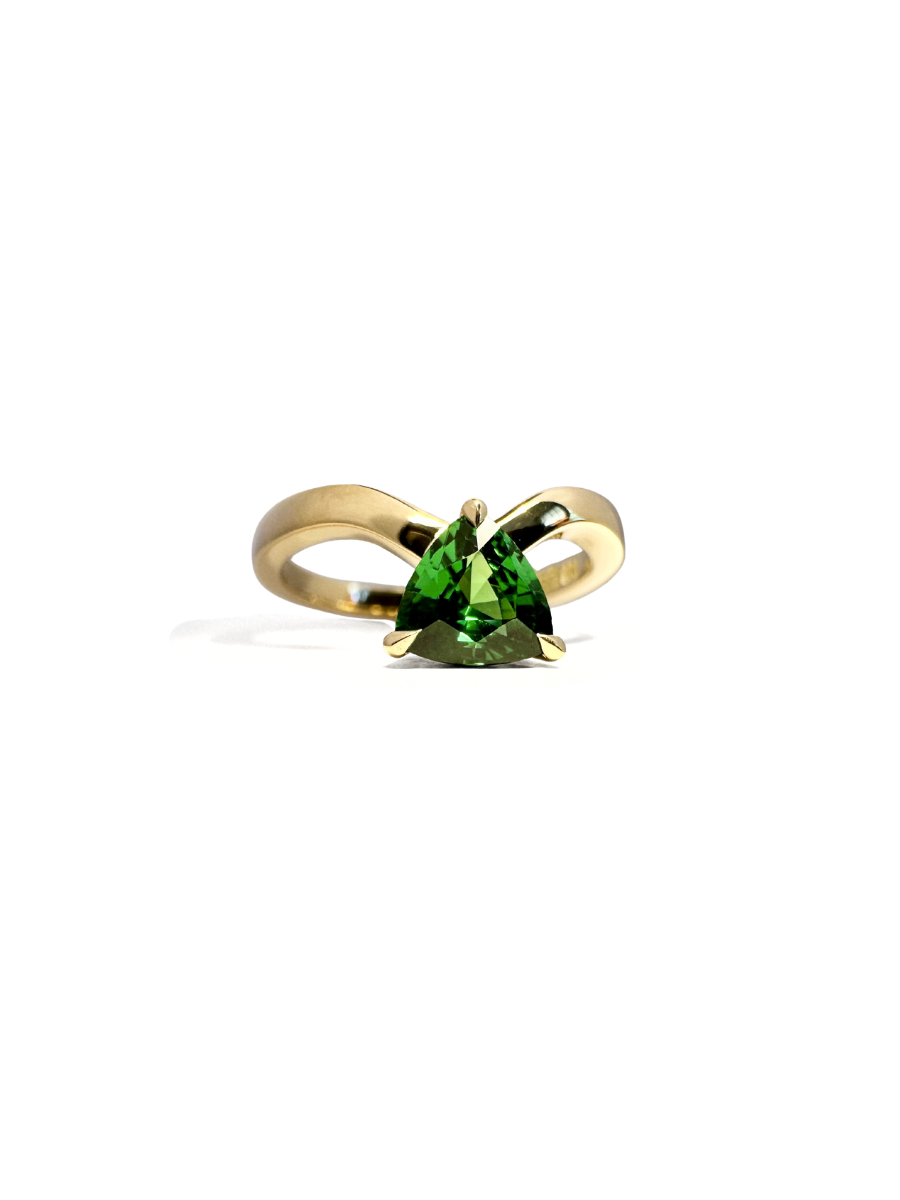 Gold ring with a green garnet on a white background